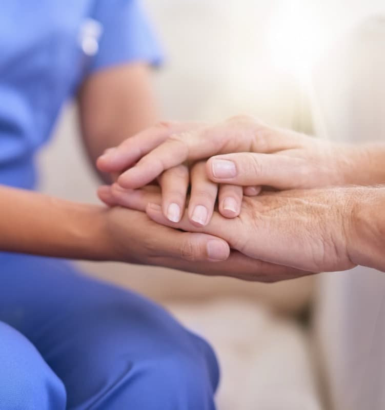 A carer holding a patient's hands in support
