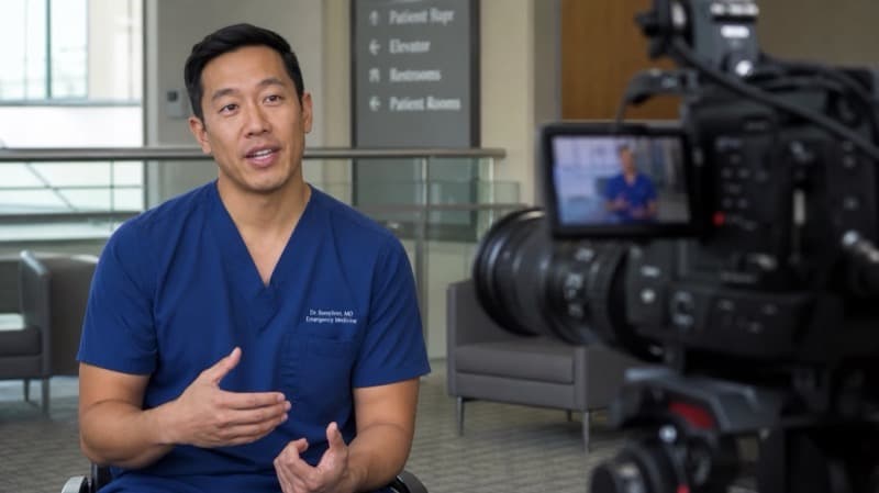 Male doctor in navy scrubs speaking to camera